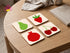 Set of 4 square cork coasters with colorful Henri Matisse style fruit paper cut-out designs on a soft cream background